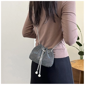 Détail d'un sac seau scintillant en strass avec chaîne argentée et breloques perles