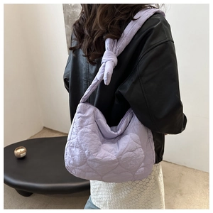 Detail of light purple quilted canvas bag featuring heart patterns and knotted shoulder strap
