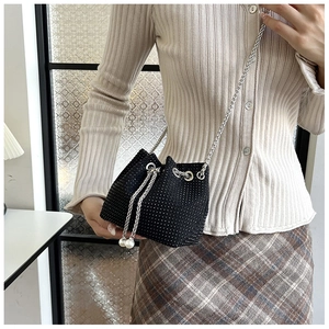 Détail d'un sac seau noir à strass avec chaîne argentée et perles sur le cordon