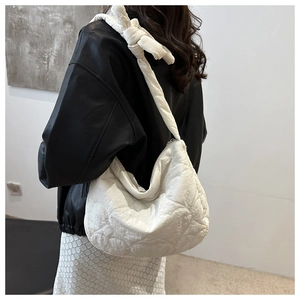 Close-up of white quilted dumpling bag featuring knot handle and nylon texture