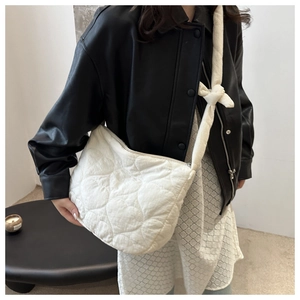 Close-up of white heart-quilted crossbody bag on model showing large capacity and soft texture