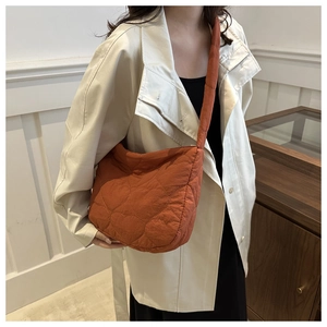 Close-up of caramel orange quilted cloud bag with large heart stitching on soft fabric