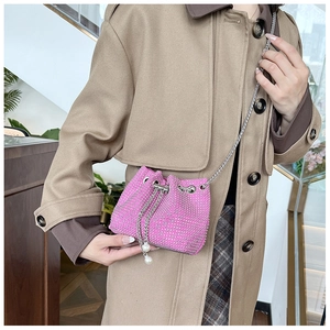 Détail du sac seau en strass rose avec bandoulière chaîne et pompons en perles