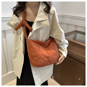 Detailed shot of an orange quilted crossbody bag with unique heart patterns and shoulder knot