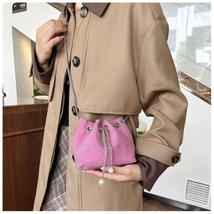 Détail du sac seau rose en strass avec cordon en perles et bandoulière chaîne argent