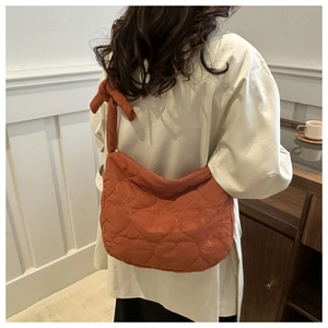 Détail du sac matelassé orange avec coutures en cœur et bandoulière à nœud décoratif
