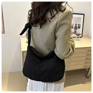 Quilted black tote bag with knot shoulder strap detail shown on a female model