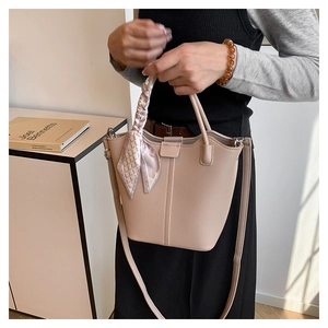 Close-up of beige lychee texture bucket bag with decorative scarf handle and shoulder strap