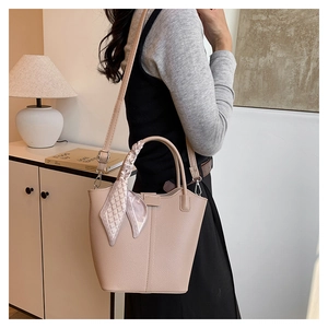 Close-up of beige lychee pattern bucket bag with chic checkered scarf on handle