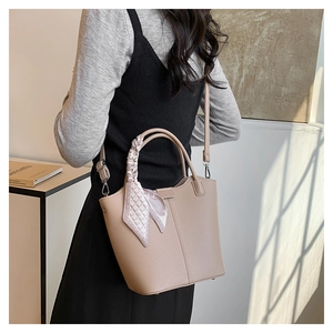 Detailed side view of beige litchi grain tote bag with decorative silk scarf on handle