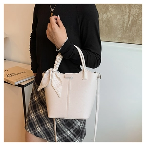 Detailed view of white lychee leather bucket bag with decorative geometric silk scarf