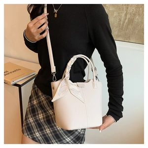 Detail of cream lychee texture bucket bag with woven handle and silk scarf decor