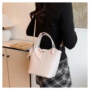Chic beige lychee grain bucket bag with woven handle and silk scarf detail