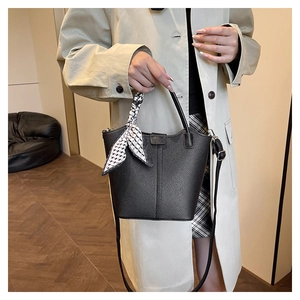 Detail of lychee pattern leather bucket bag with decorative scarf and shoulder strap