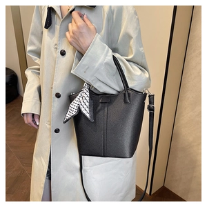 Detail view of black lychee leather bucket bag with silk scarf on the top handle