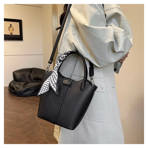Detail of black lychee-patterned bucket bag with geometric silk scarf and shoulder strap