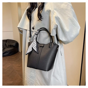 Close-up of black lychee grain bucket bag with silk scarf and detachable strap on model