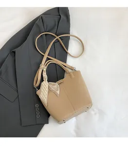 Detail of khaki lychee grain leather bucket bag with metal studs and silk scarf
