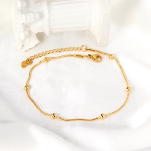 Minimalistisches 18K vergoldetes Schlangen-Fußkettchen mit Goldperlen auf weißer Seide