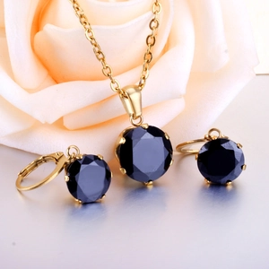Detail of gold six-prong jewelry set with round black gemstones and pendant necklace