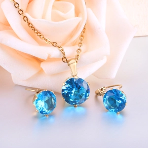 Elegant six-prong sapphire necklace and earrings set displayed with a pink rose