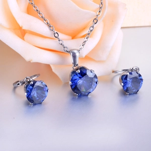 Detail view of sapphire blue six-prong pendant necklace and matching huggie earrings