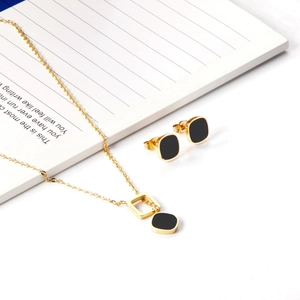 Detail of elegant gold necklace and earring set featuring square black inlay pendants