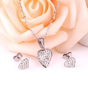 Vue macro d'un ensemble collier et boucles d'oreilles cœur en zircon sur fond de rose