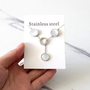 Detailed view of silver Y-shaped stainless steel necklace with white shell inlay pendants