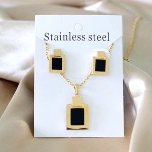 Detail of gold-plated stainless steel jewelry set with black geometric rectangle charms