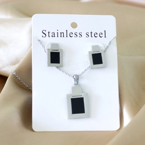 Detailed set of stainless steel square necklace and earrings on white card and silk