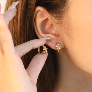 Créoles en acier inoxydable doré avec pendentif fleur et zircons blancs sur modèle
