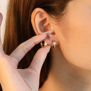 Gros plan de boucles d'oreilles étoile à huit branches dorées avec zircon sur mannequin