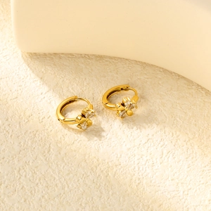 Détail de boucles d'oreilles créoles dorées ornées de fleurs serties de zircons