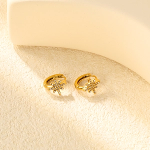 Détail de boucles d'oreilles étoile à huit branches dorées avec zircons blancs incrustés