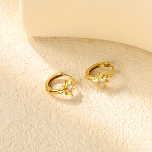 Détail des boucles d'oreilles créoles dorées avec pendentif étoile et zircons blancs