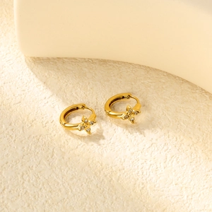 Détail de boucles d'oreilles fleurs dorées avec étoiles en zircon sur socle en pierre