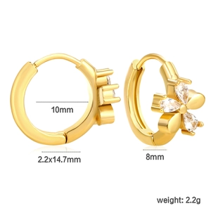 Détail de boucles d'oreilles créoles dorées avec pendentif papillon et zircons poire