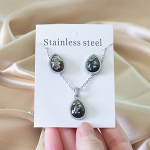 Detail of waterdrop pendant set with iridescent stone inlay on champagne satin fabric
