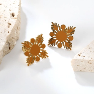 Gros plan de boucles d'oreilles fleur dorées sur pierre blanche et fond épuré