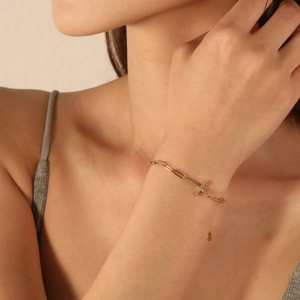 Gold paperclip chain bracelet with shimmering pavé cross pendant and heart-shaped charm