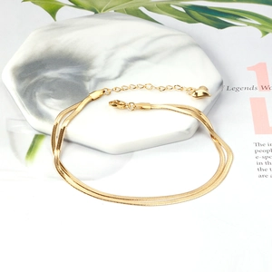 Detailed view of double layered gold snake chain anklet with a heart charm on marble tray