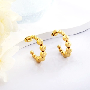 Detailed view of gold plated stainless steel beaded C-shaped hoop earrings on a stand