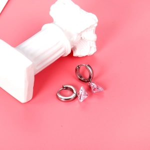 Minimalist silver hoop earrings with dangling pink heart zirconia on a marble pedestal
