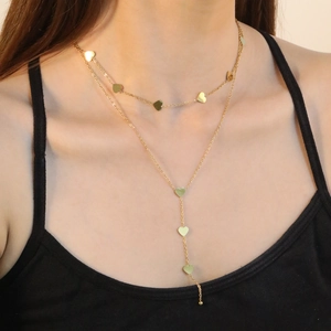 Elegante collana doppia dorata con ciondoli a cuore e lunghe nappe su una modella