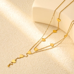 Dettaglio di una collana con ciondolo a cuore dorato su un supporto beige ruvido