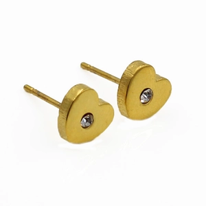Détail macro d'une boucle d'oreille cœur dorée avec fini brossé et cristal central