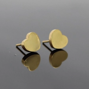 Vue macro des boucles d'oreilles cœur dorées avec finition miroir et surface polie brillante
