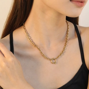 Detail of 18K gold plated flat snake chain featuring a large round spring clasp on a model