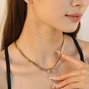 Detailed macro view of an 18K gold-plated flat snake chain with decorative spring ring clasp